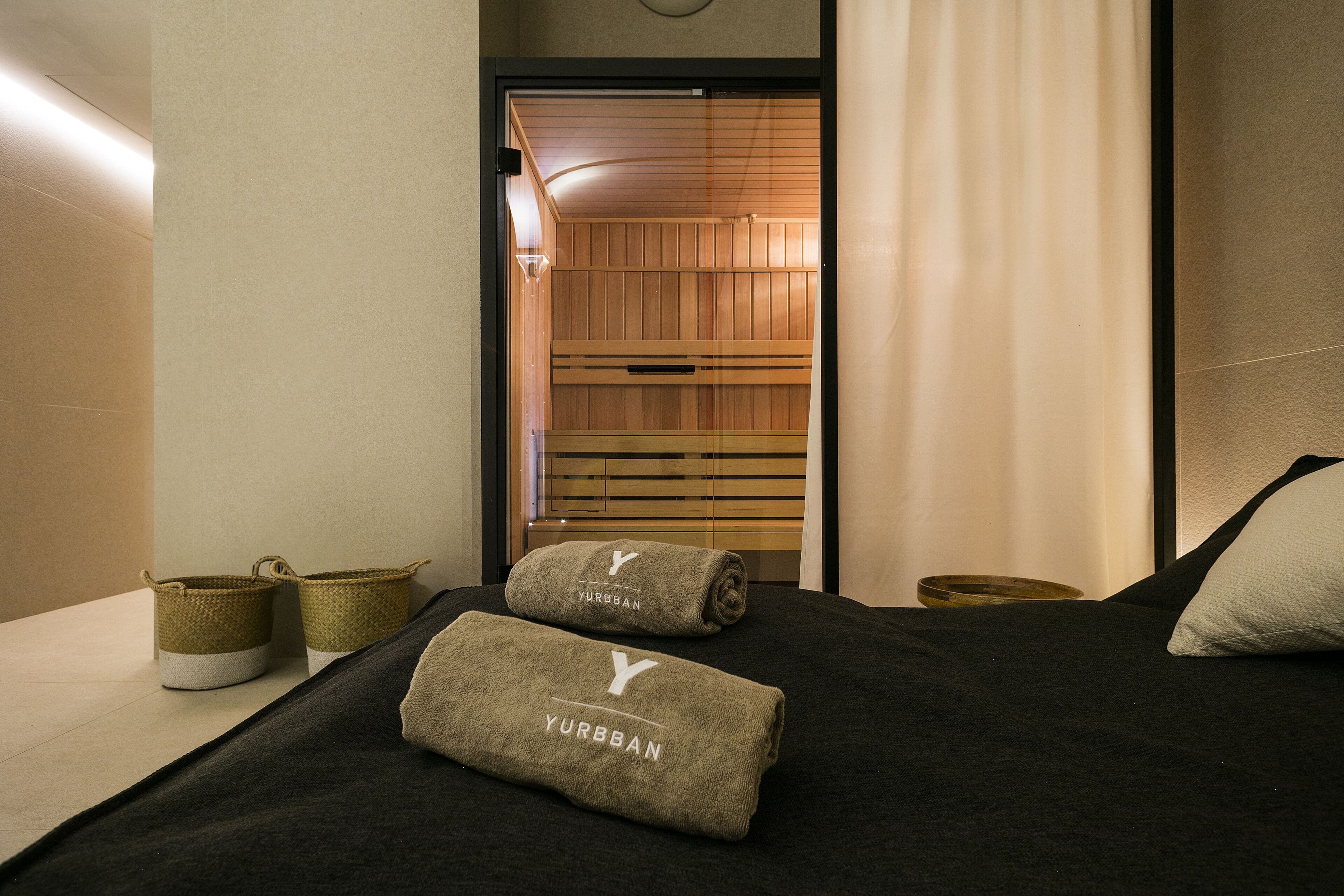 A hotel room with a bed, two towels, and two baskets.