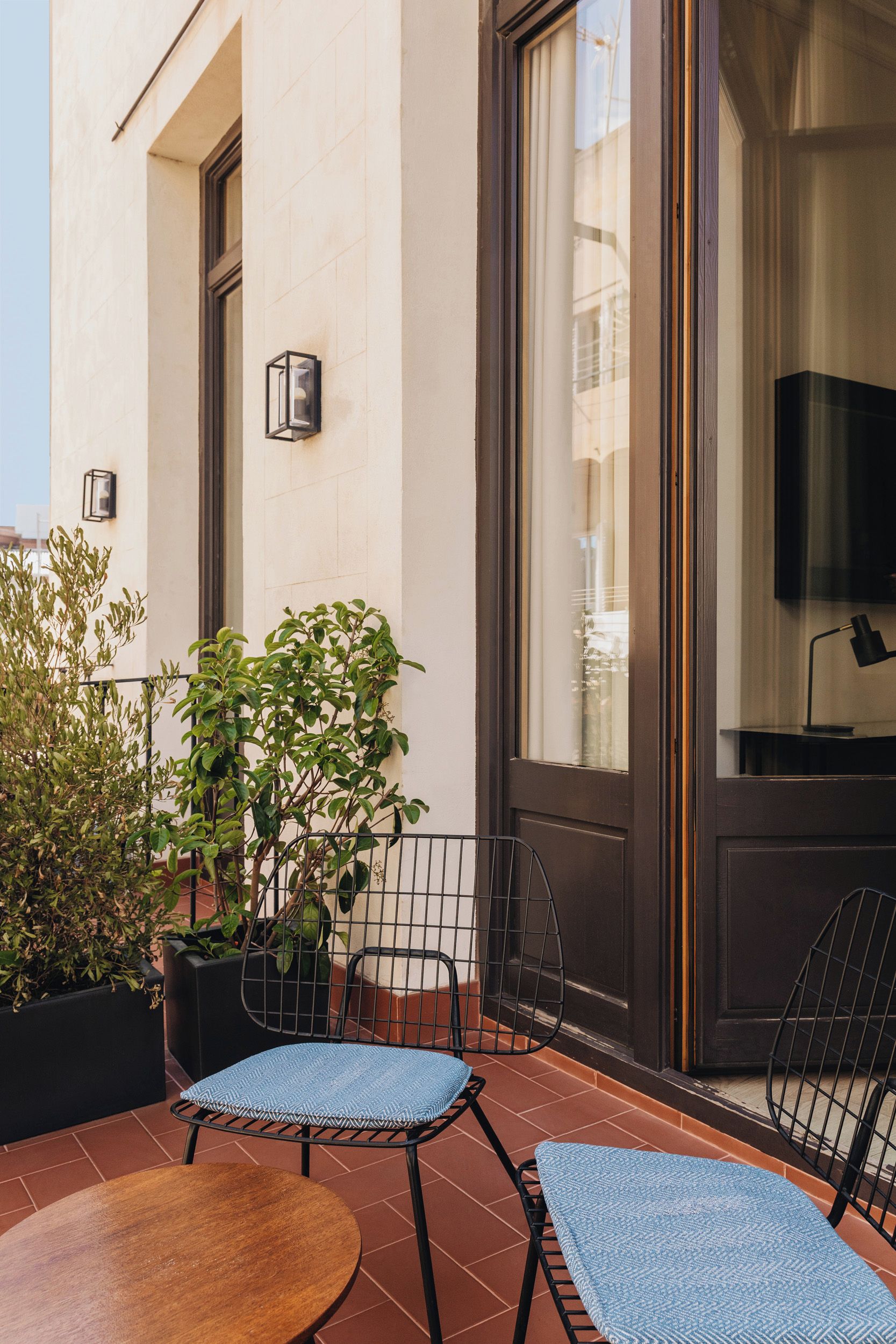 Une terrasse avec deux chaises, une table et des plantes en pot.