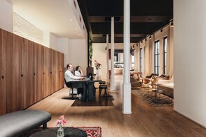 Interior moderno com parede de madeira, área de estar central com mesa e cozinha ao fundo.