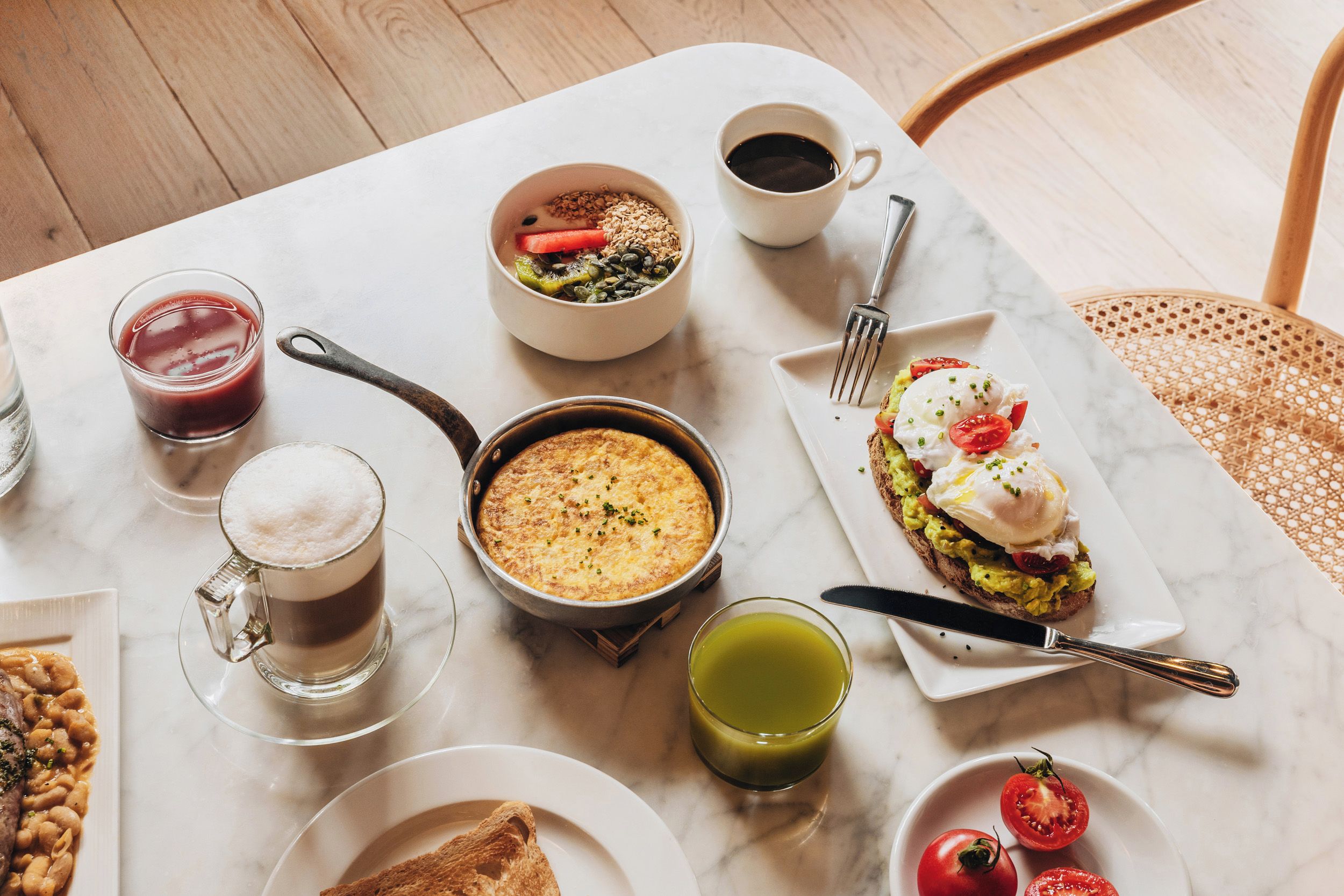 Uma mesa de mármore com diversas opções de comida e bebida para o pequeno-almoço.