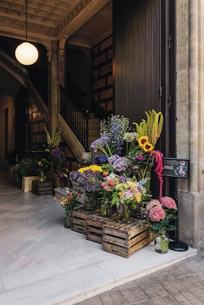 Arranjo floral em um hall de entrada com uma escada e uma placa indicando 'Passage Flowers'.