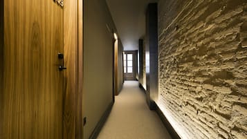 A hallway with a wooden door labeled "209", a textured wall, and a carpeted floor.