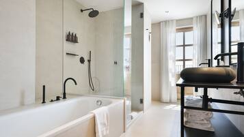 Une salle de bain moderne avec une baignoire, une douche à l’italienne en verre et un meuble-lavabo doté d’un plan de toilette noir.