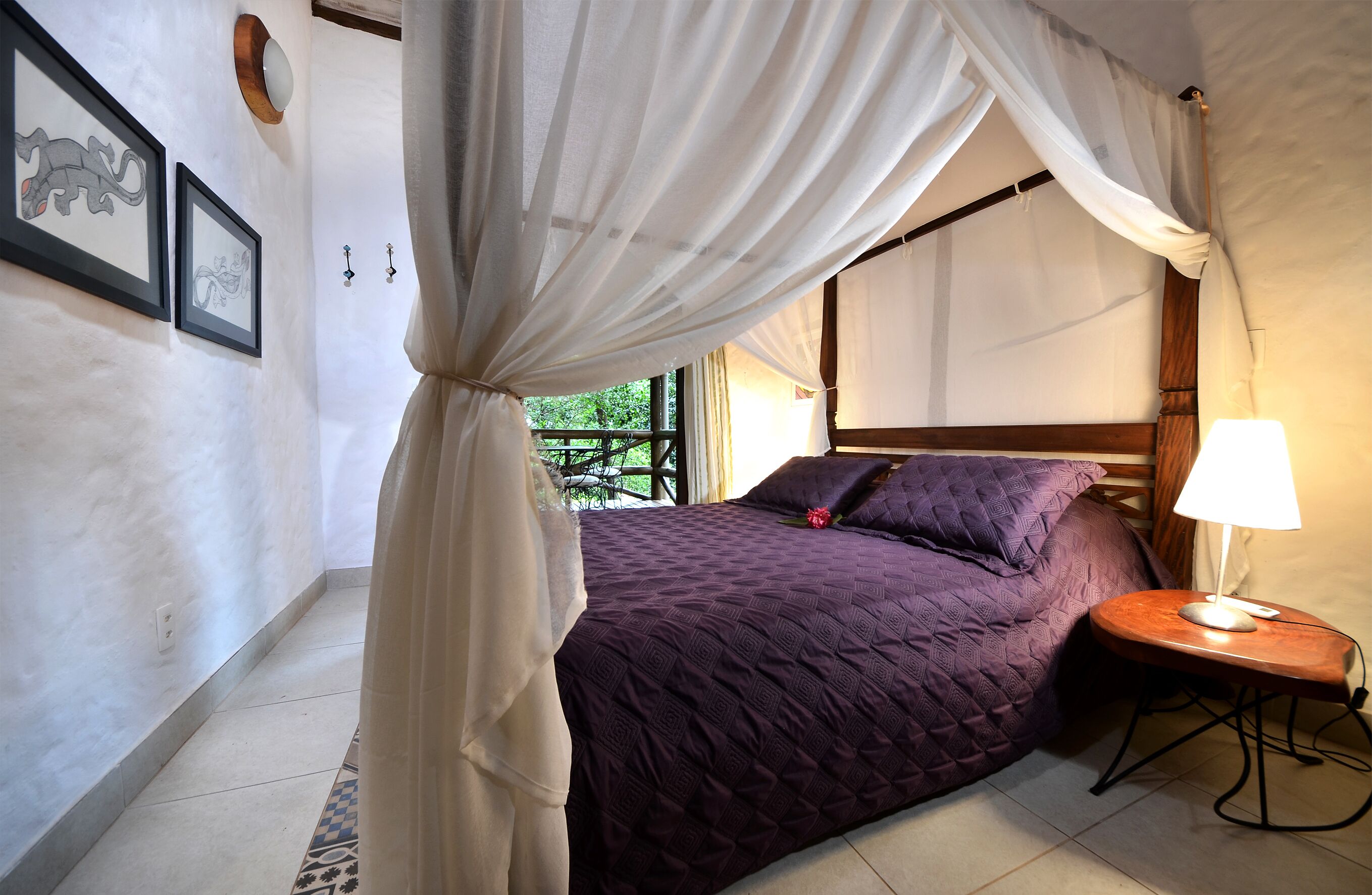 A bedroom with a bed, a bedside table with a lamp, and a window with curtains.