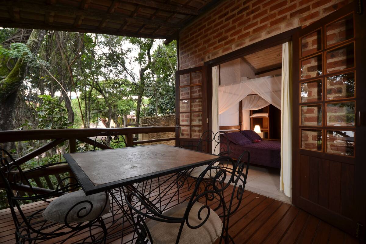 A wooden deck with a table and chairs, a brick wall, and a bed with a canopy.