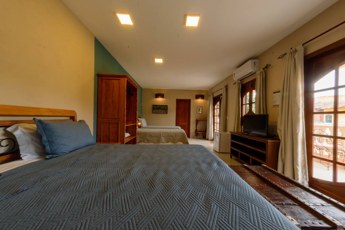 A bedroom with two beds, a television, and a window with curtains.