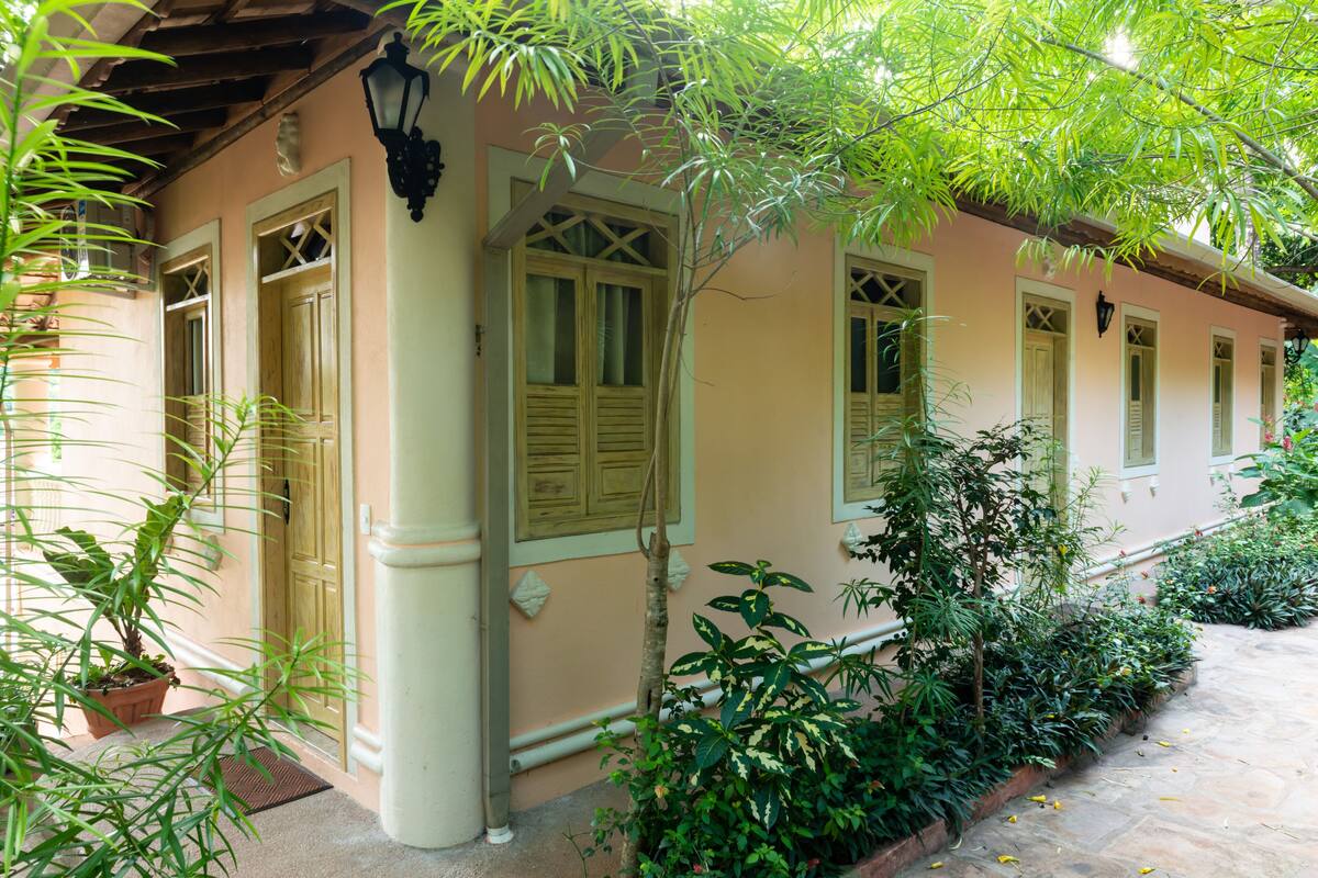 A building with multiple windows and doors, surrounded by greenery.