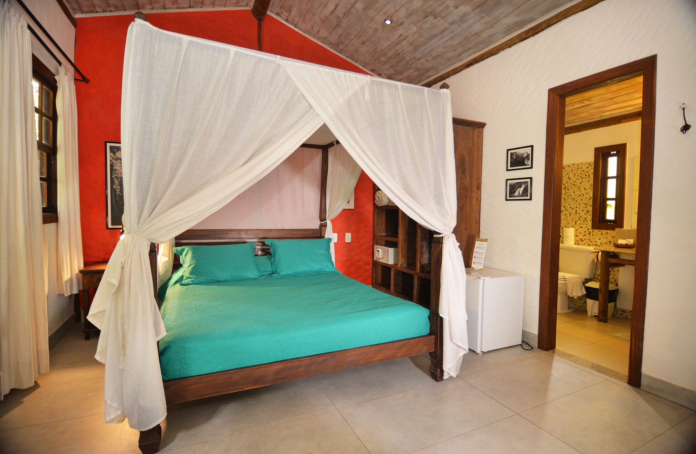A room with a bed, a small white cabinet, and a bathroom visible through an open door.