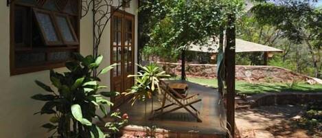 Una casa con porche de madera, una planta en maceta y una pequeña mesa.