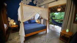 Une chambre à coucher avec un lit à baldaquin, une vue sur la verdure par la fenêtre et un hamac à l’extérieur.