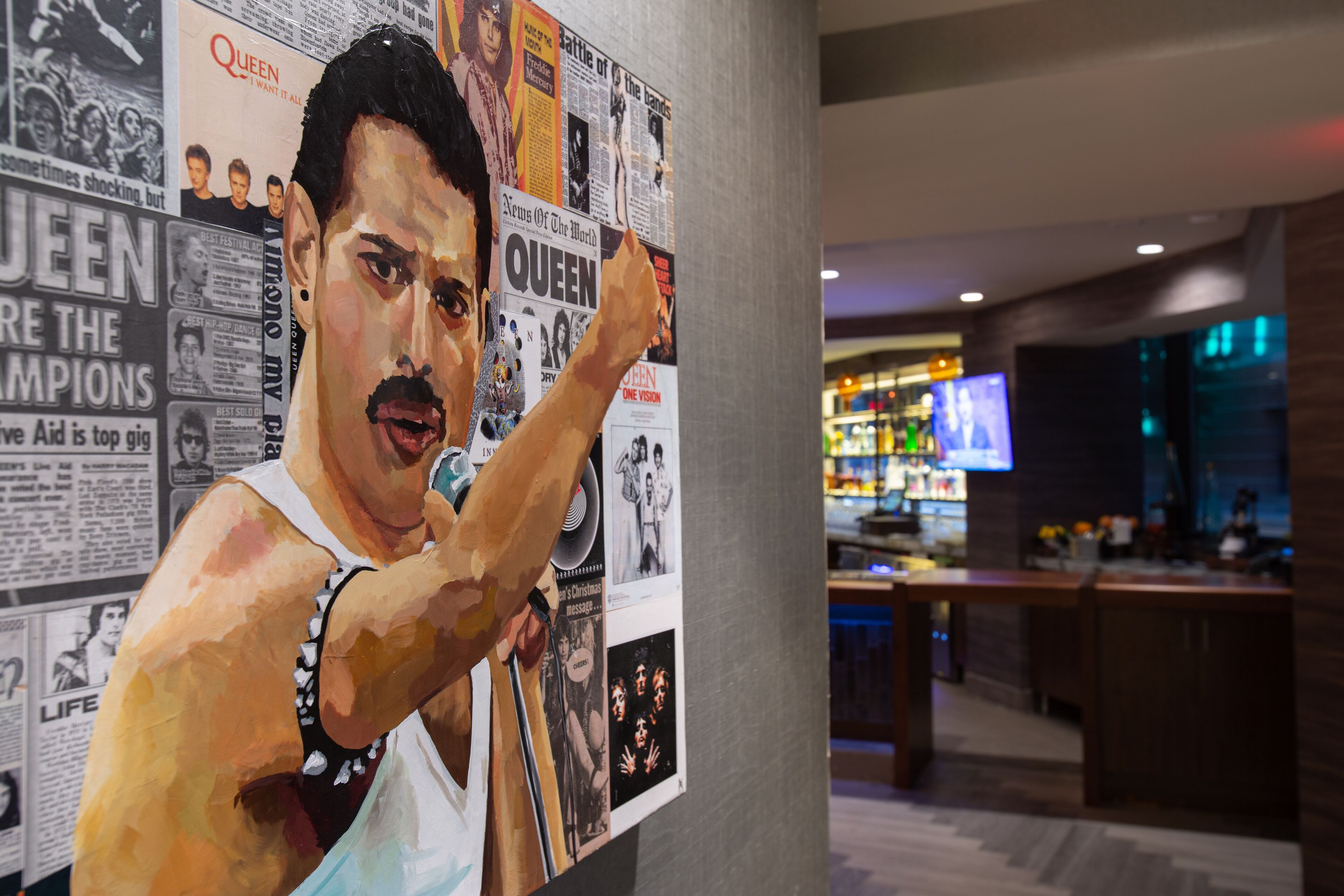 A wall with various posters and a person painting.