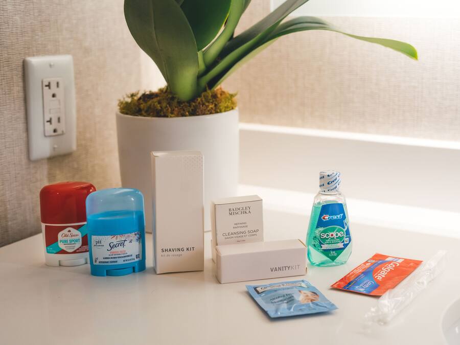 A bathroom counter with a shaving kit, Crest mouthwash, Old Spice body wash, Secret deodorant, and alcohol-free moisturizer.