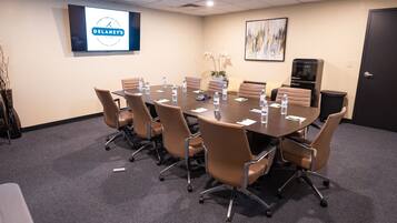 A conference room with a large table, brown chairs, a projector screen, and a Galanz refrigerator.