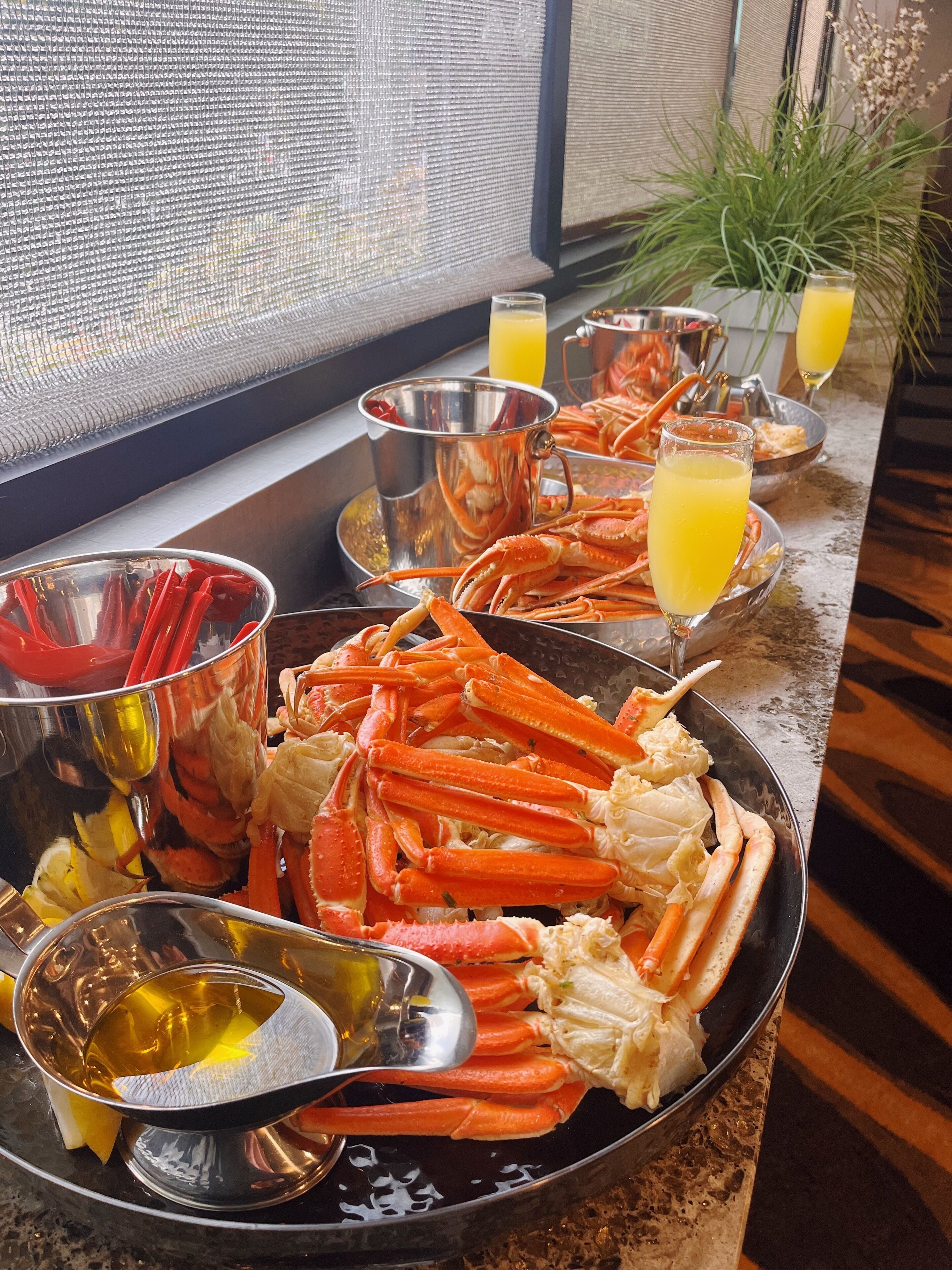 A seafood platter with crab legs, lemon wedges, and a glass of orange juice on a table.