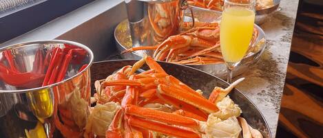 A seafood platter with crab legs, lemon wedges, and a glass of orange juice on a table.