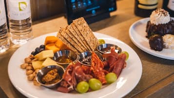 Un piatto con assortimento di formaggi, salumi e frutta secca su un tavolo di legno.