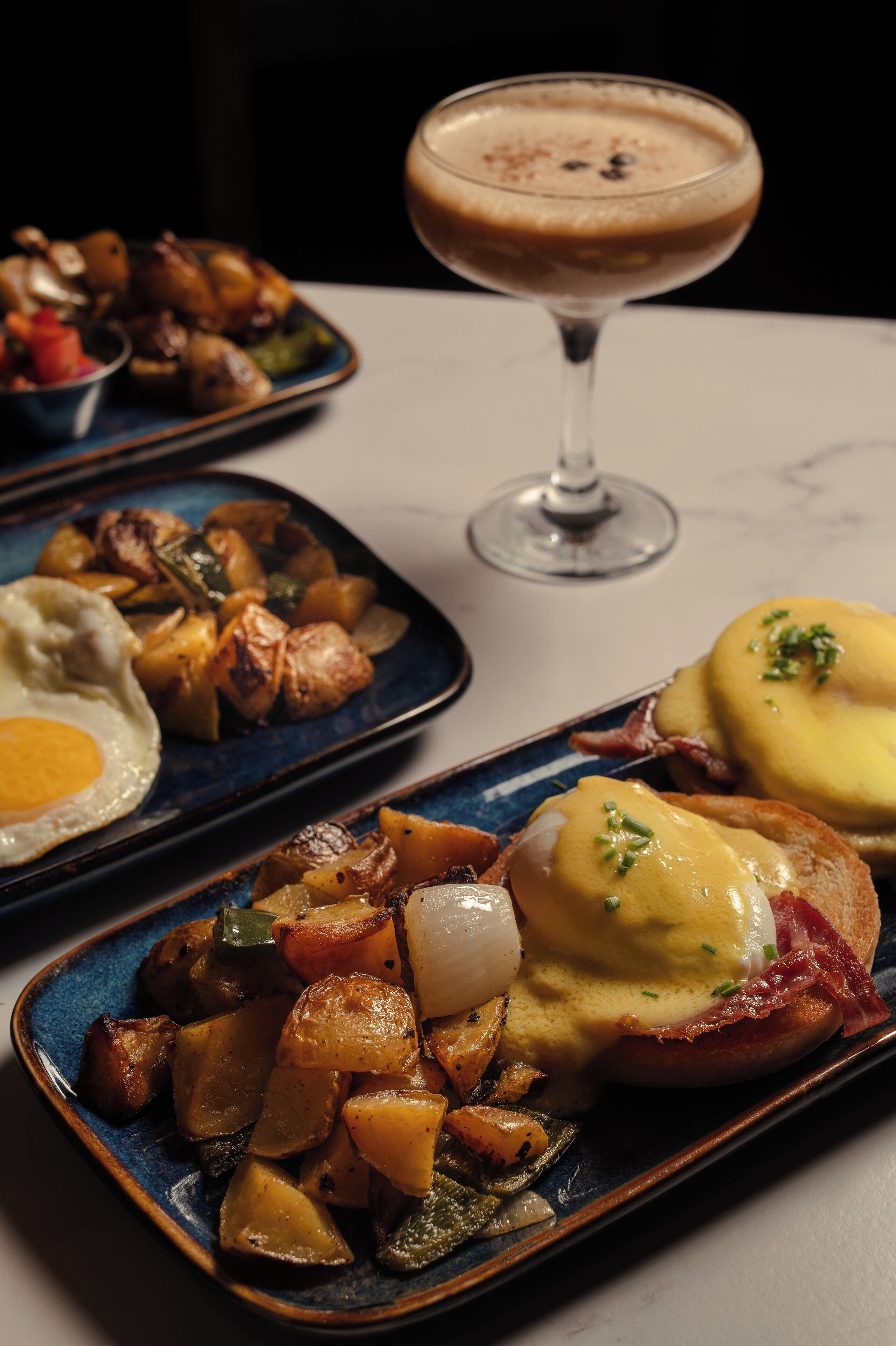 Ein Tisch mit Frühstücksgeschirr, darunter Eier, Kartoffeln und ein Getränk.