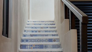 Un escalier recouvert de carreaux bleus et blancs formant un motif, menant à un palier.