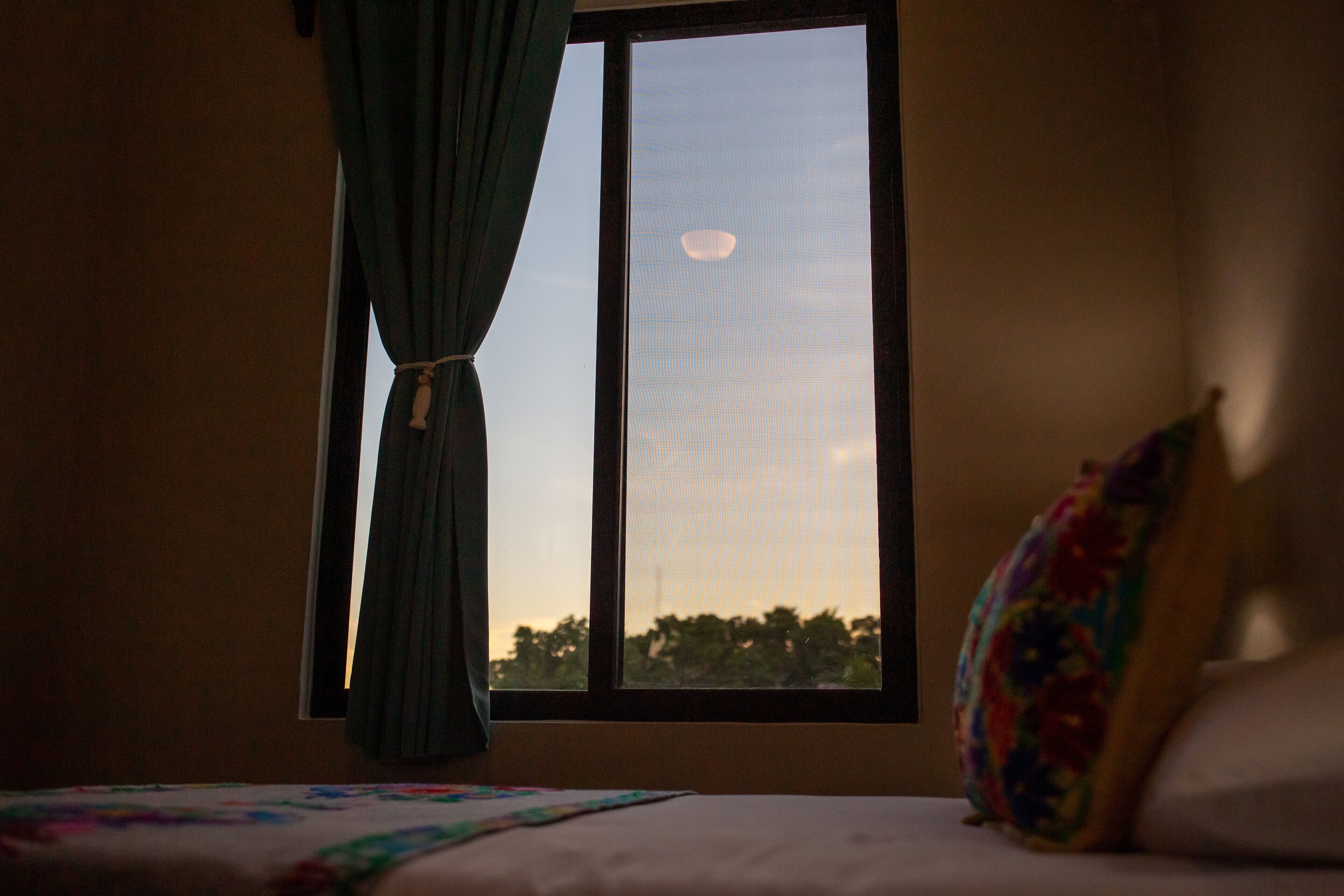 A room with a bed, a window, and a curtain.