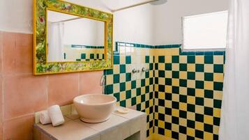Une salle de bain avec un mur recouvert de carreaux à motifs, un lavabo avec un bac blanc et un miroir doté d’un cadre décoratif.