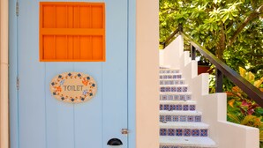 Une porte bleue avec un panneau indiquant les toilettes, un escalier recouvert de carreaux décoratifs et une rampe métallique.