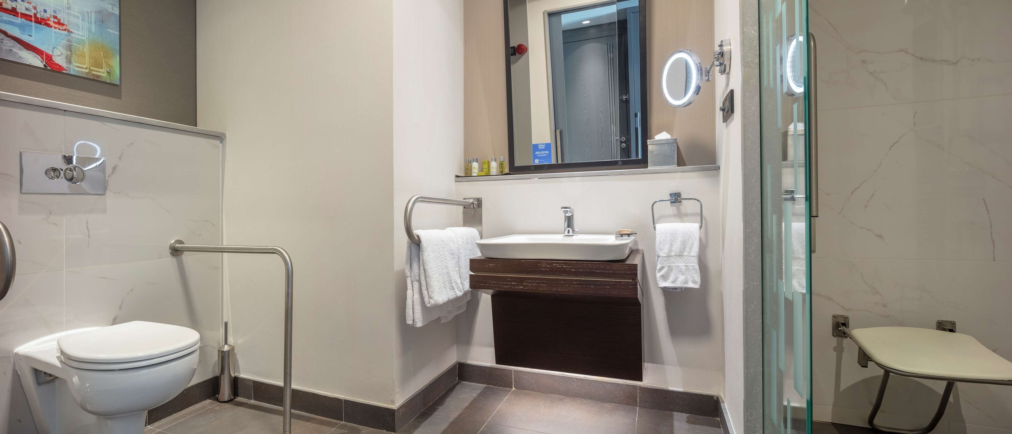 A modern bathroom with a toilet, sink, and glass shower enclosure.