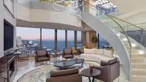 A spacious lounge area with a curved staircase, comfortable seating, and a view of the cityscape and water. - Hilton Istanbul Bakirkoy (Istanbul)