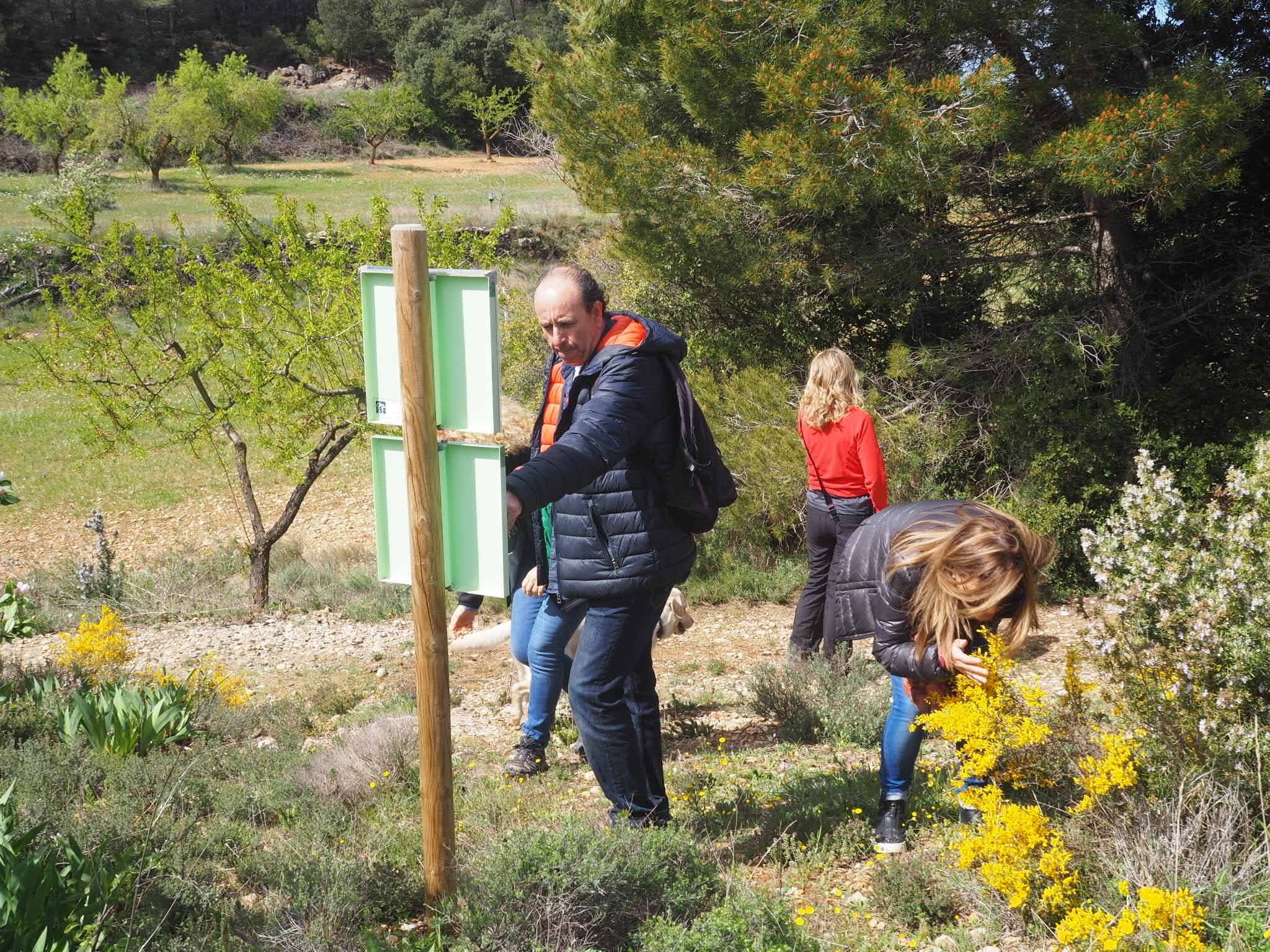 A group of people in a natural setting with a wooden structure and greenery.