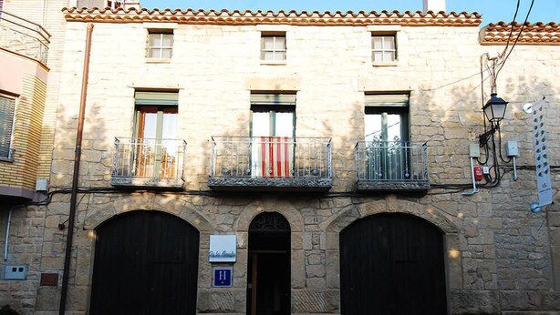 A stone building with two balconies, a central door, and a sign indicating a hotel. - Vilosell Wine Hotel (El Vilosell)