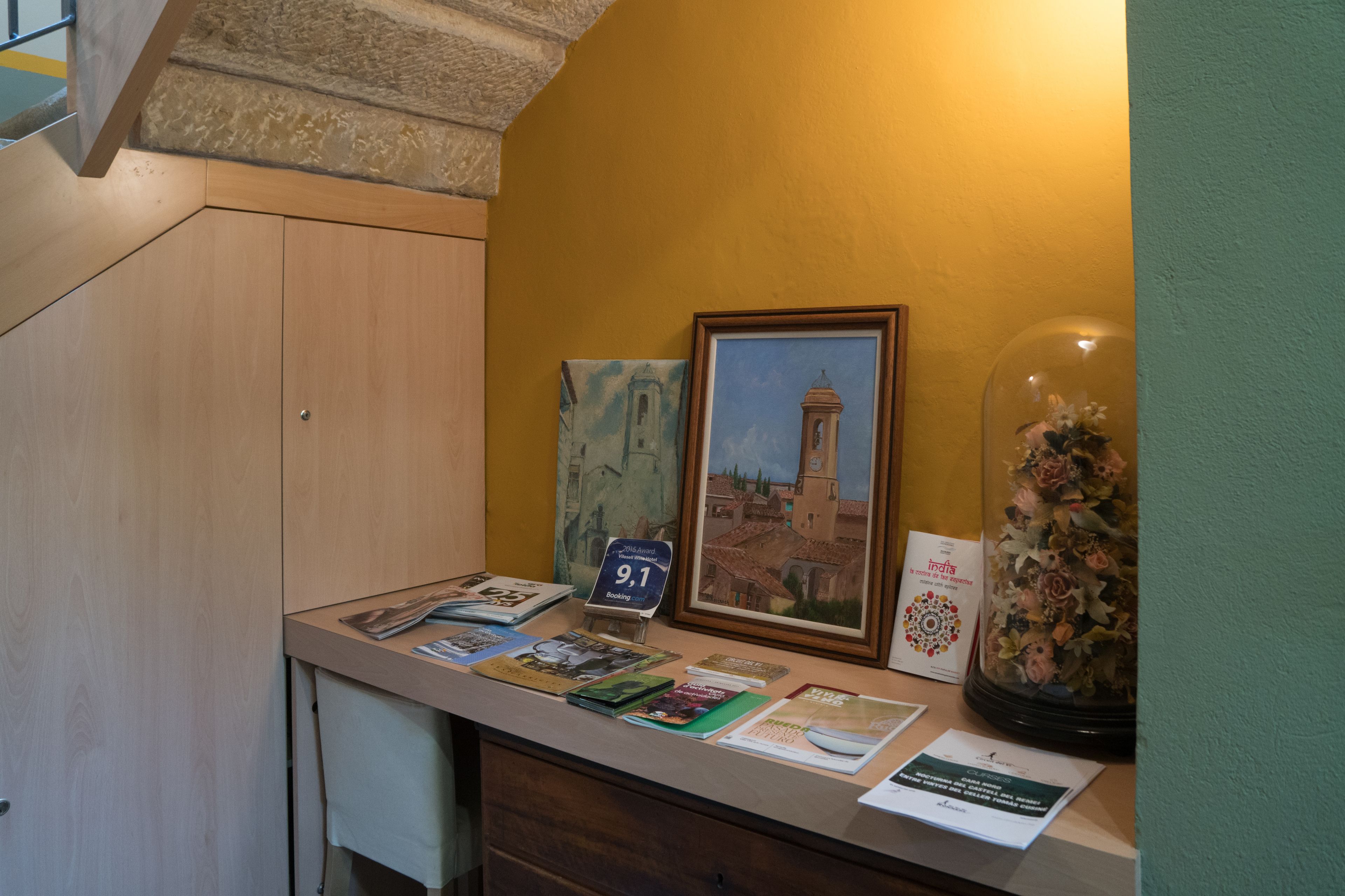 Een receptiebalie met een lijstbeeld van een toren, een glazen koepel met bloemen en diverse brochures.