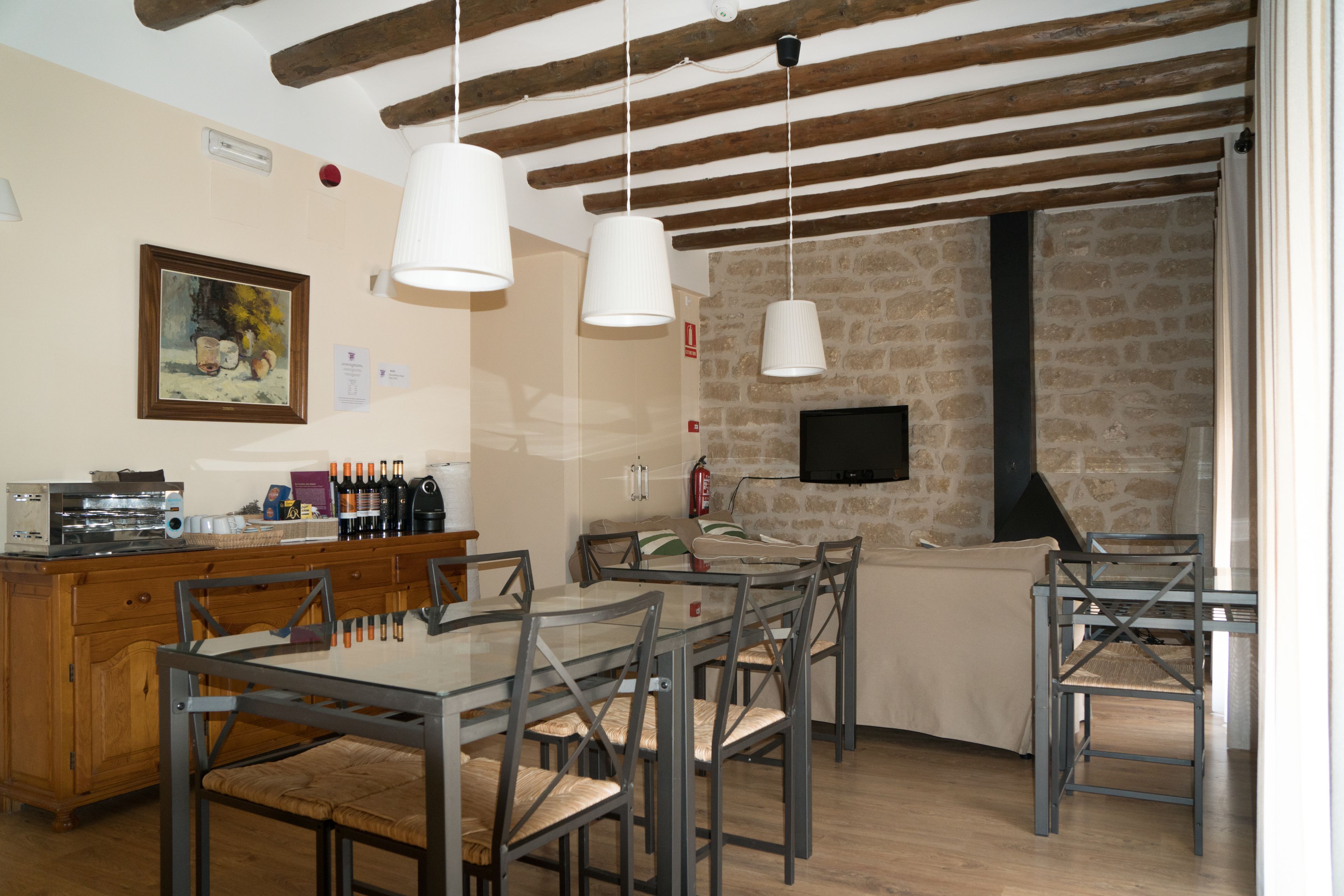 Un comedor con una mesa y sillas de madera, una pared de piedra y un televisor montado en la pared.