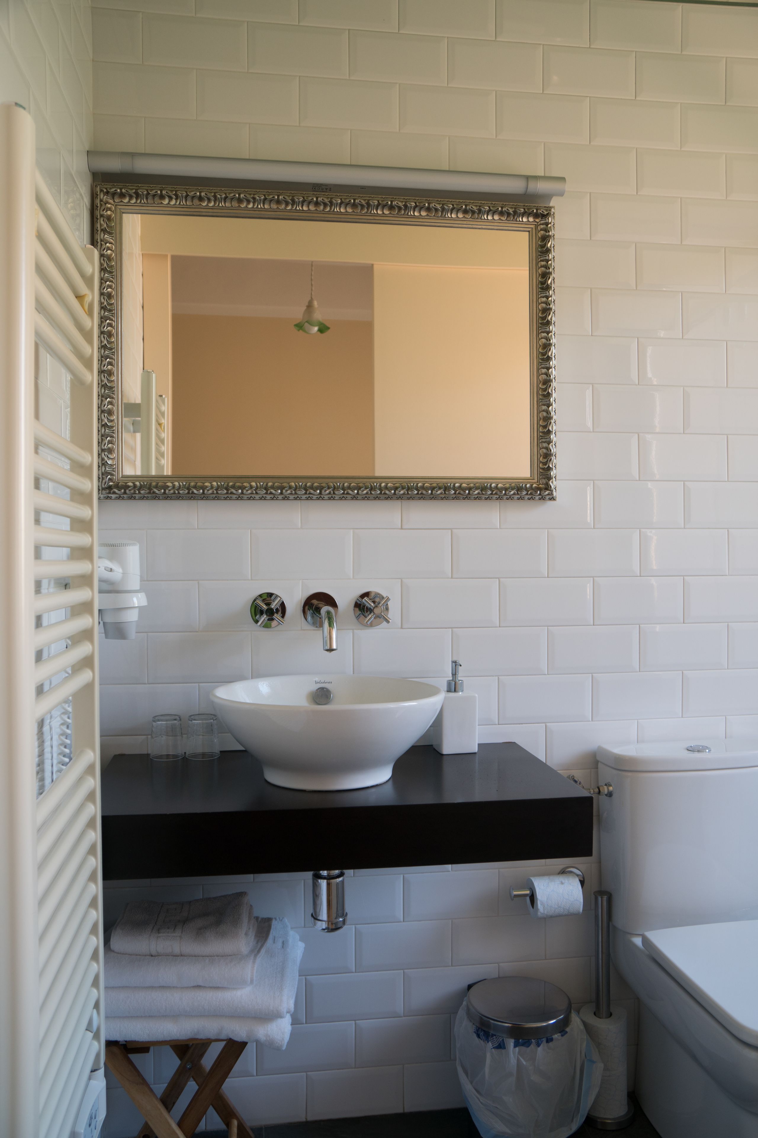 A bathroom with a white sink, black countertop, and a mirror above it.