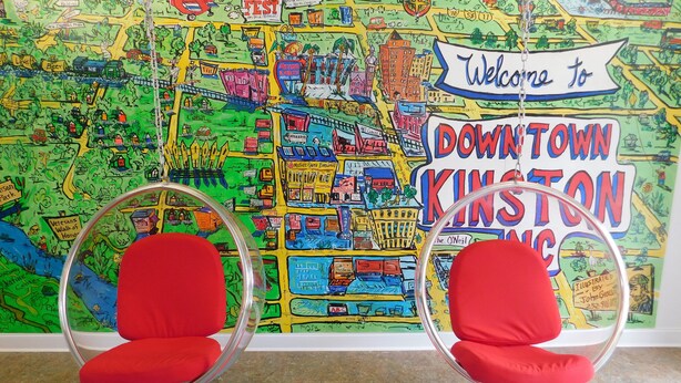 Two red chairs in front of a colorful map mural with 'Welcome to Downtown Kinston NC' text. - Mother Earth Motor Lodge (Kinston)
