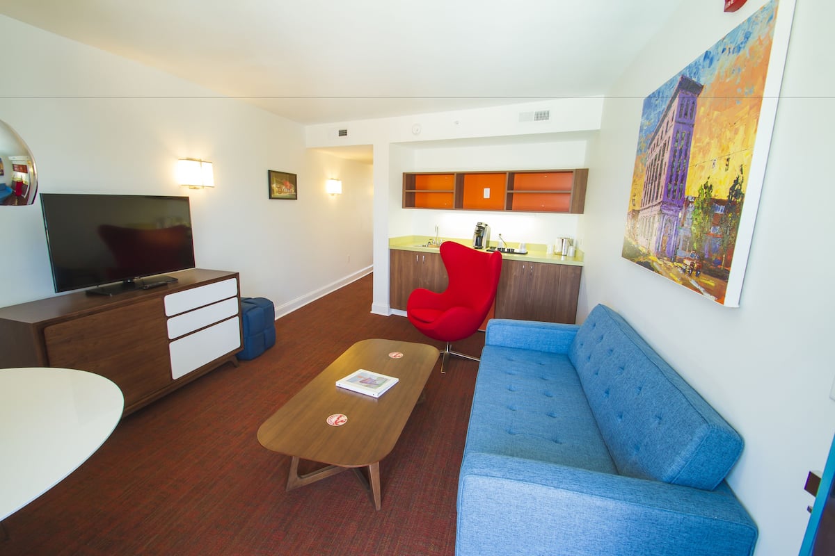 A modern living room with a TV, sofa, coffee table, and a red chair.