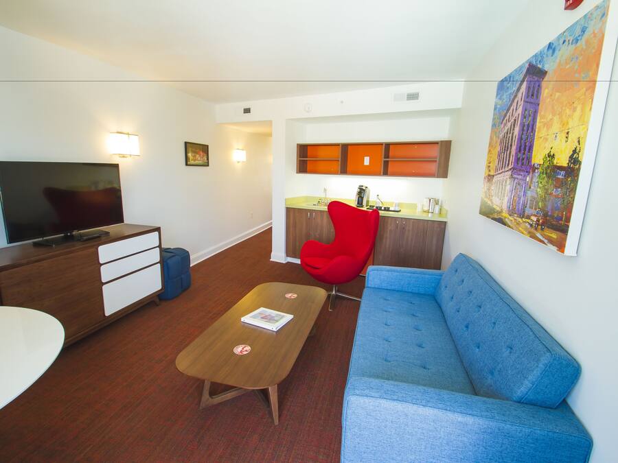 Una sala de estar moderna con televisor, sofá, mesa de centro y una butaca roja.