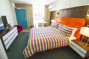 A hotel room with a bed, a desk, a chair, a TV, and a window with curtains. - Mother Earth Motor Lodge (Kinston)