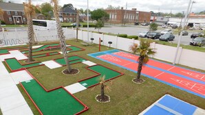 A mini-golf course with multiple green and red holes, a tennis court, and a ping pong table. - Mother Earth Motor Lodge (Kinston)