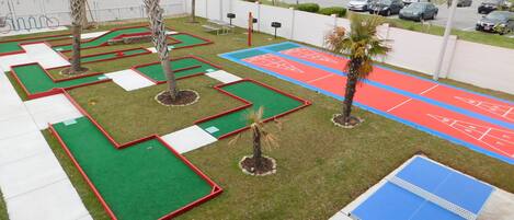 A mini-golf course with multiple green and red holes, a tennis court, and a ping pong table.