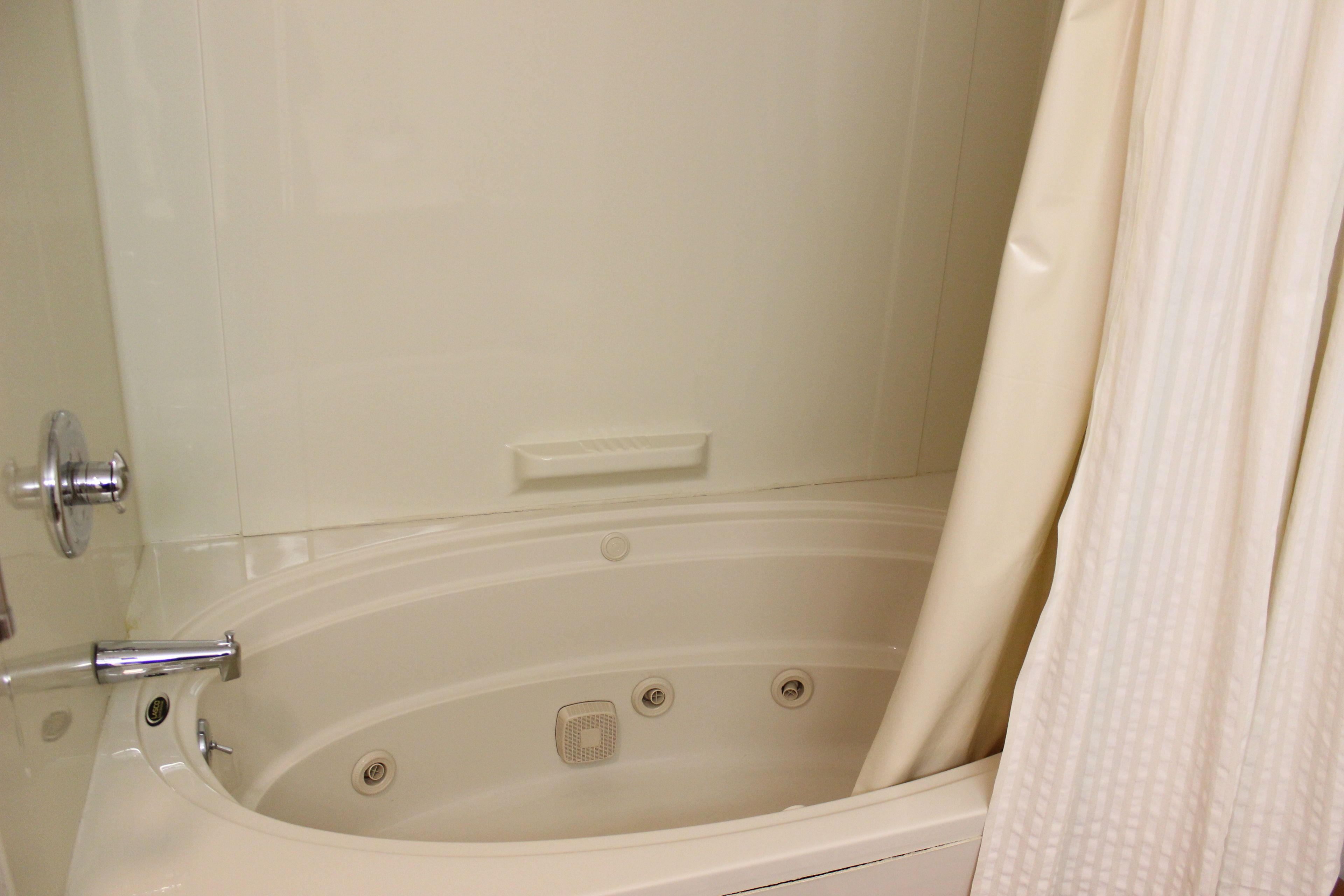 Una bañera con cortina de ducha, un grifo y un panel de control.