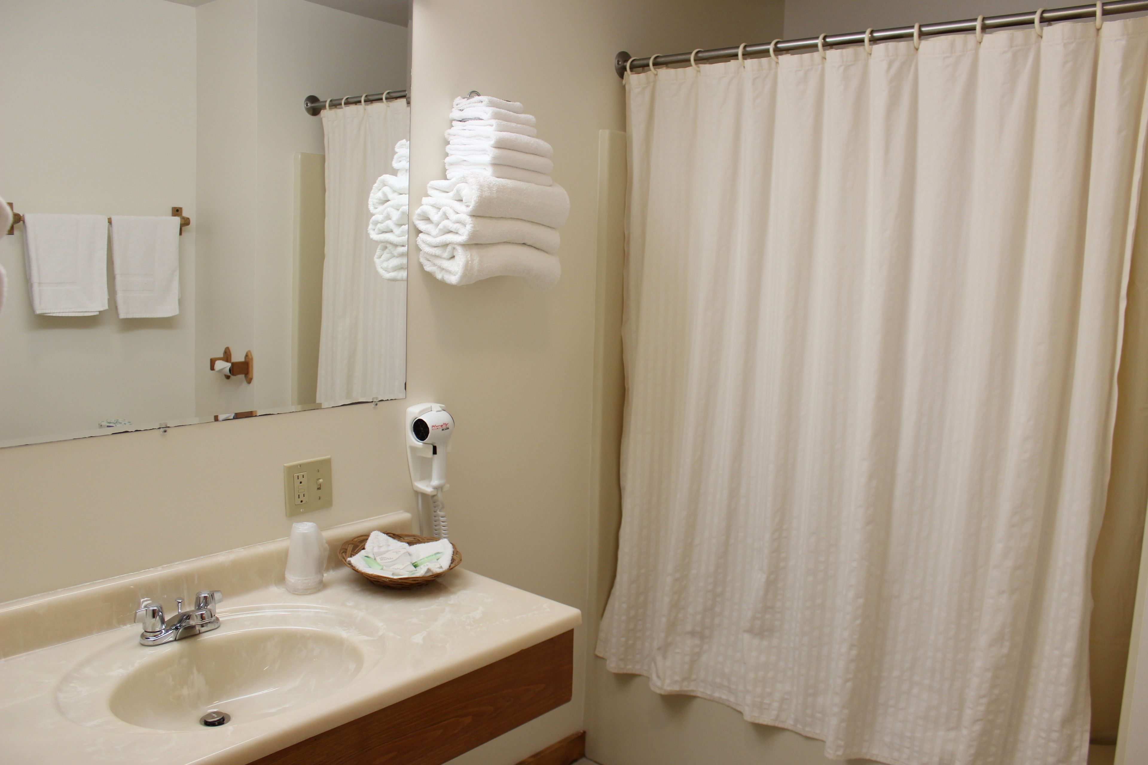 A bathroom with a sink, mirror, towel rack, and a shower curtain.