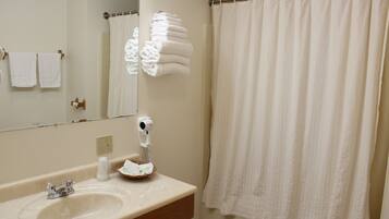 A bathroom with a sink, mirror, towel rack, and a shower curtain.