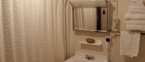 A bathroom with a shower curtain, a sink, a mirror, a towel rack, and a toilet.