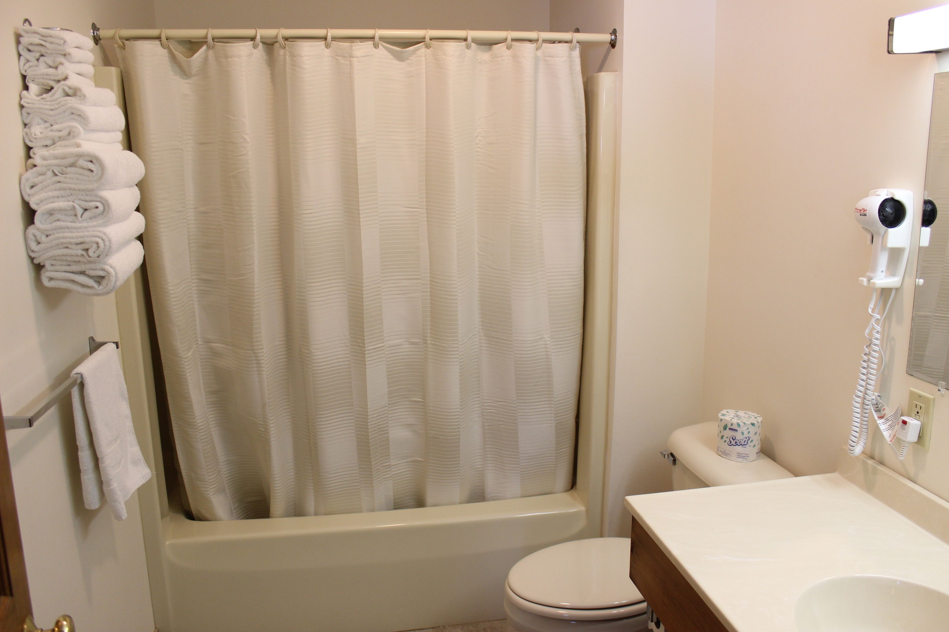 A bathroom with a bathtub, toilet, and a towel rack with folded towels.