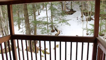 Una terraza de madera con vista a un bosque nevado.