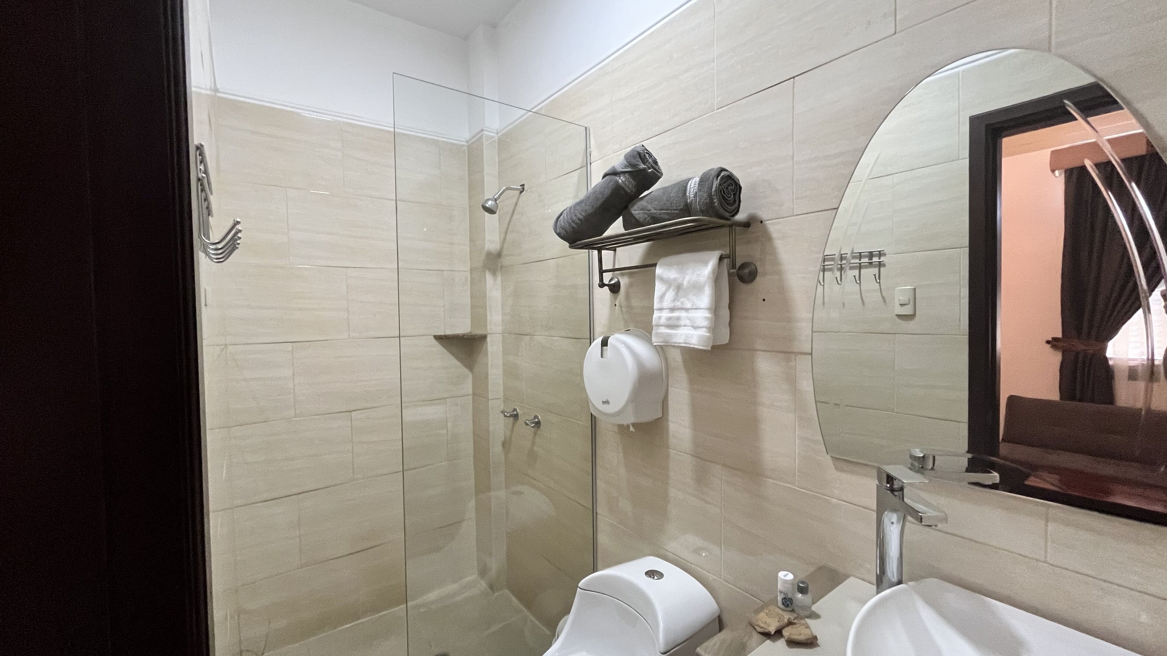 Un baño moderno con cabina de ducha de vidrio, inodoro, lavabo y toallero.