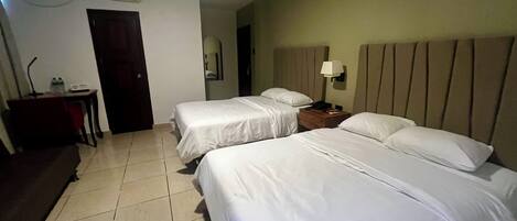 Habitación de hotel con dos camas, un escritorio, una silla, una lámpara y un equipo de aire acondicionado.