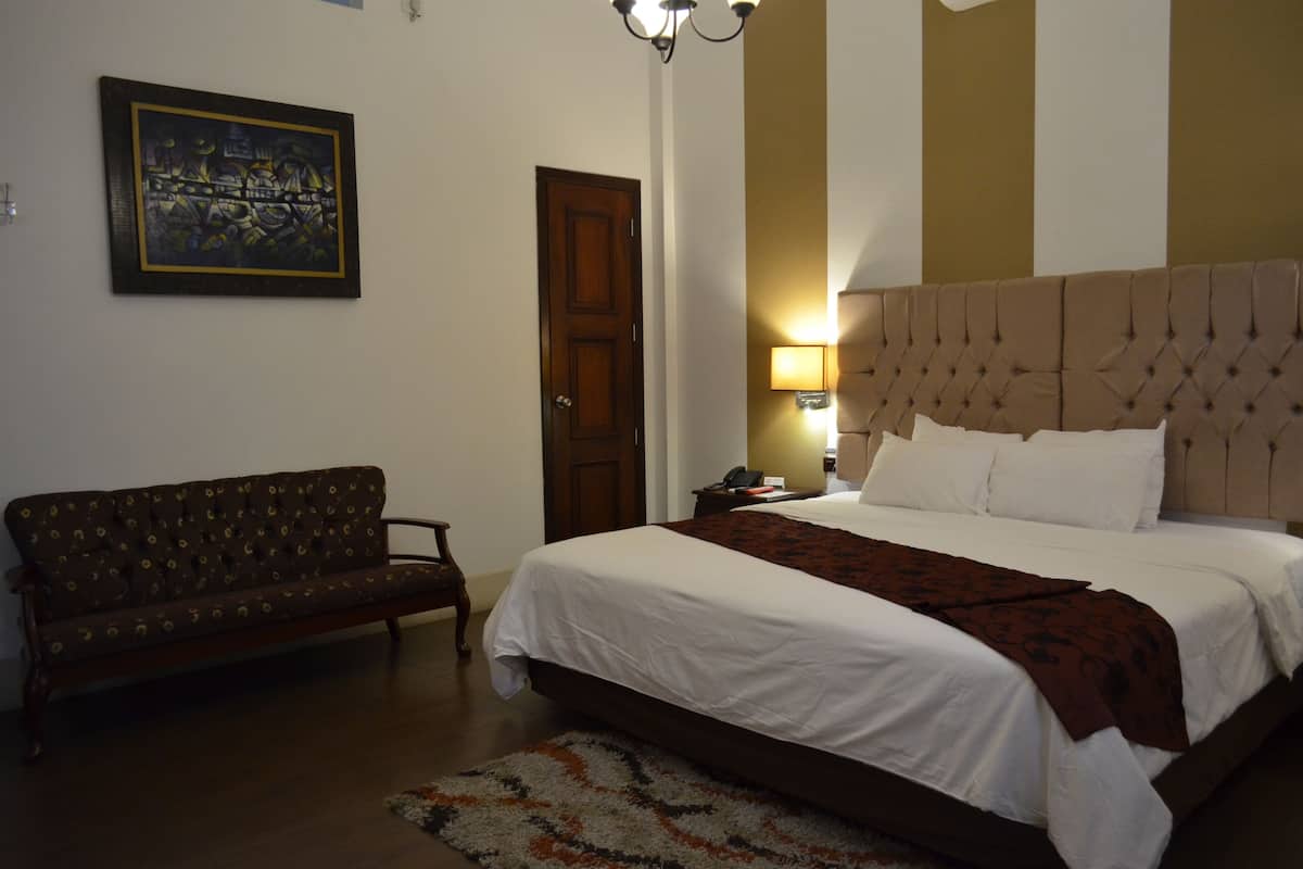 Un dormitorio con cama, sofá, una puerta y una lámpara de pared.