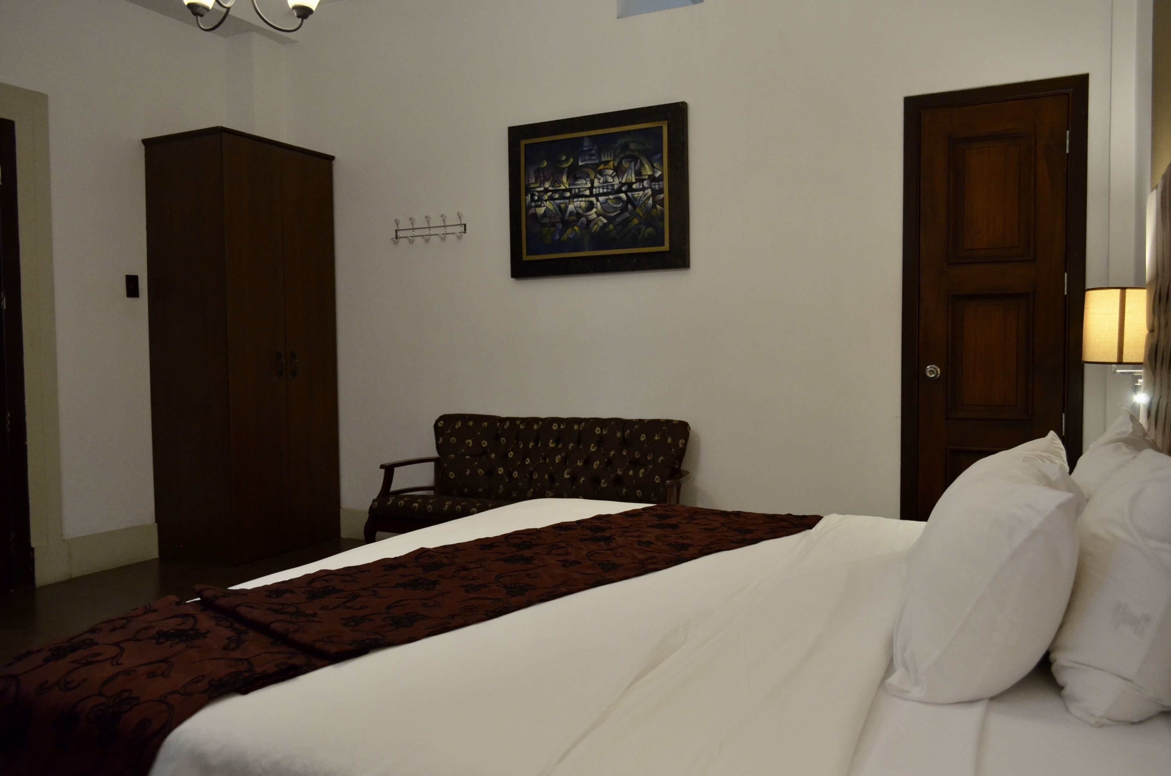 Une chambre d’hôtel avec un lit, une commode, un canapé, un tableau au mur et une porte.