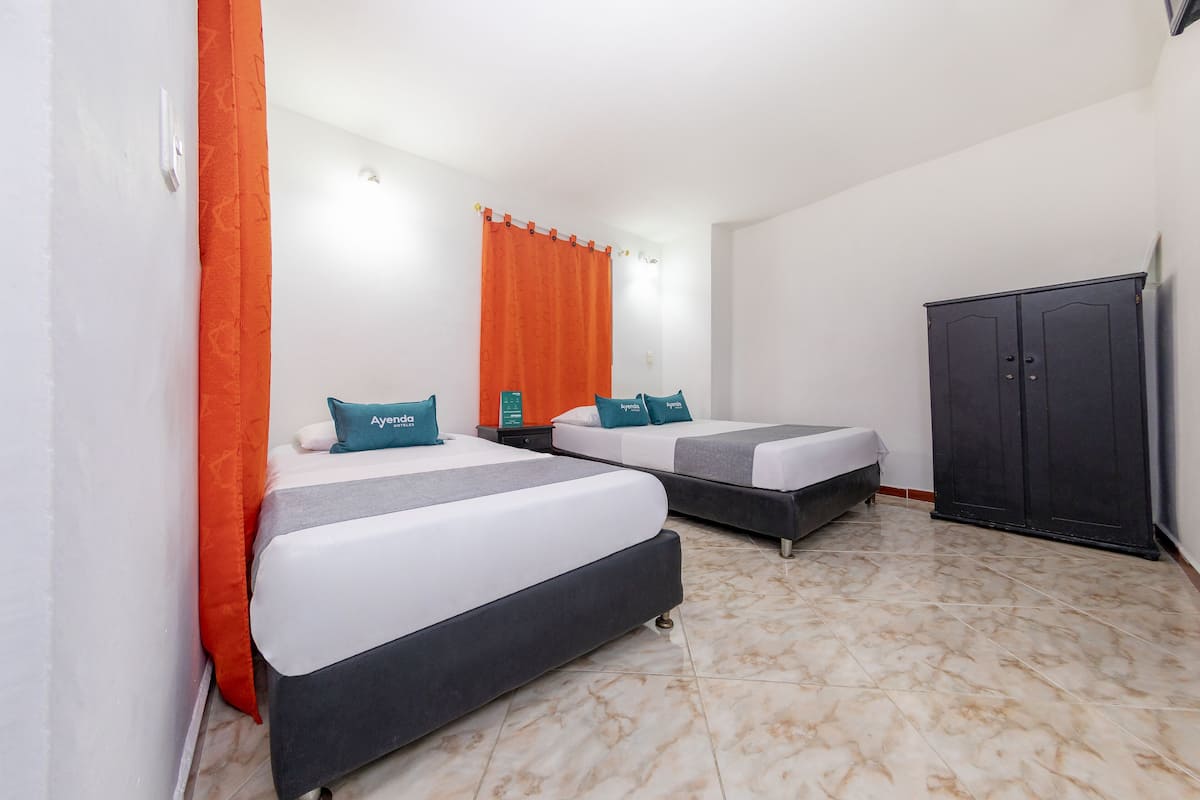Habitación de hotel con dos camas, cortinas naranjas, un armario oscuro y suelo de baldosas.