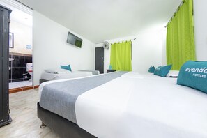 Une chambre d’hôtel avec deux lits, une télévision, un ventilateur et un rideau vert.